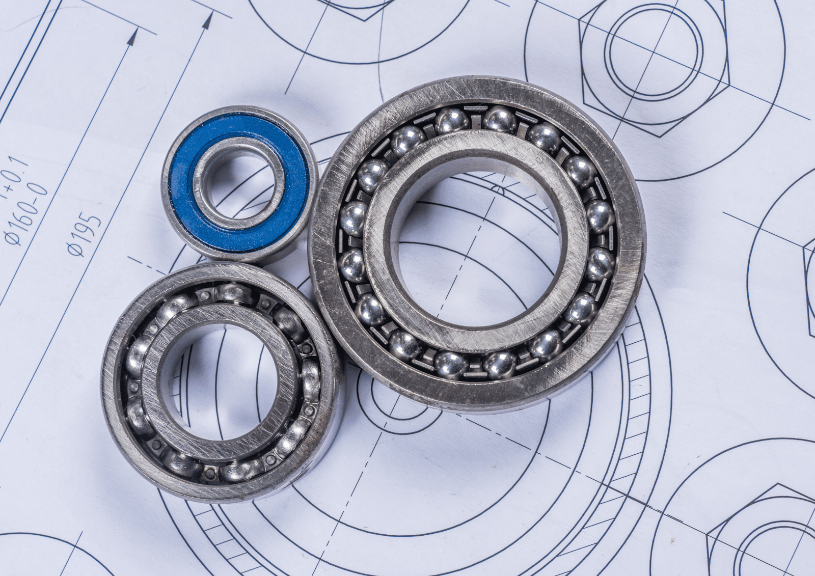 Close-up of ball bearings on technical blueprints, showing metallic rings and a blue seal.
