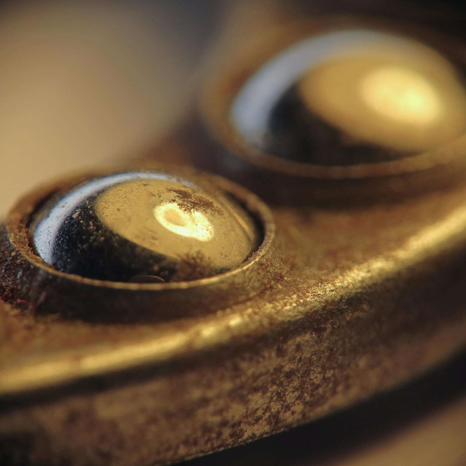 Close-up macro shot of yellowed brass screws on a rusted metal surface, with shallow depth of field.